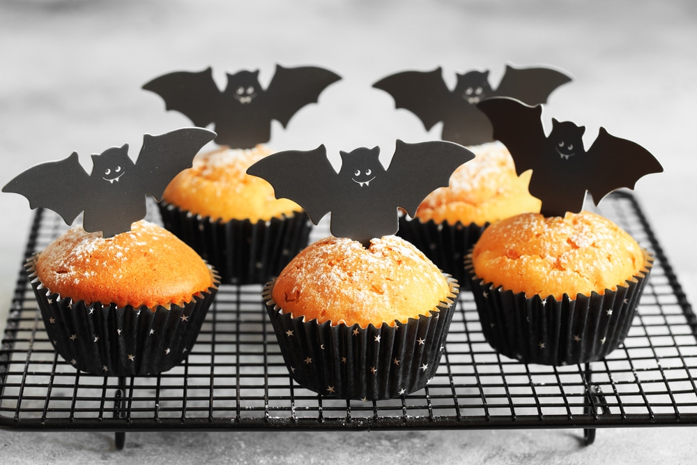 Muffins de abobora de Halloween em capsulas pretas decoradas com morcegos de papelao