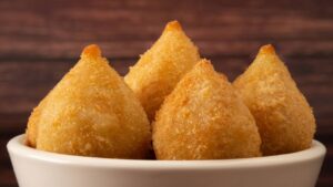 Uma coxinha dourada, macia e com aquele recheio quentinho que chega perfumando tudo