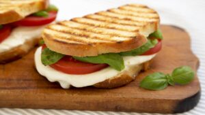 Torrada caprese com tomate suculento, muçarela derretendo e manjericão fazendo a festa no aroma