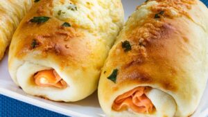 Uma massinha quentinha que abraça presunto e queijo até formar um rolinho dourado e irresistível